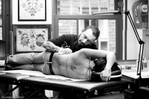 Un tatuatore esercita la sua professione all'interno di uno studio di tatuaggi